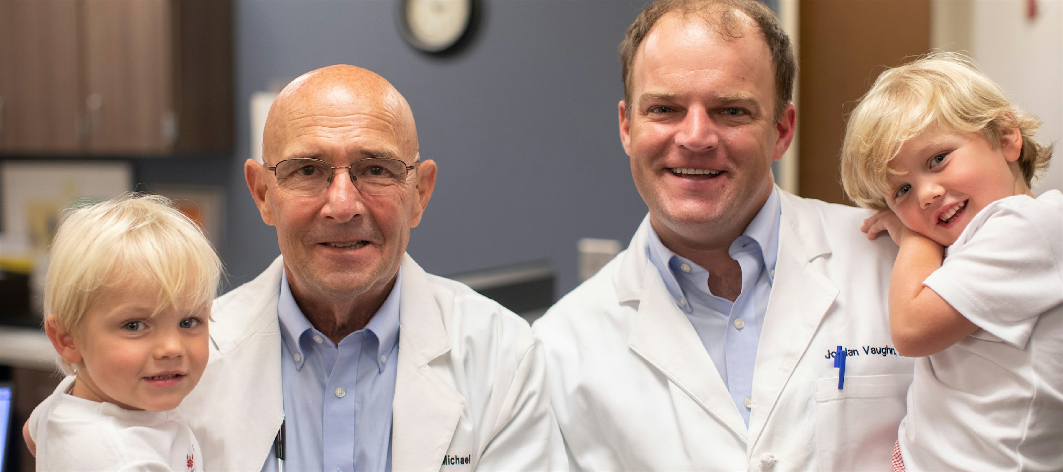 Michael Vaughn and Jordan Vaughn smiling at MedHelp Urgent Care holding two children