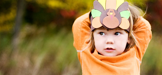 child in orange shirt wearing turkey hat craft at thanksgiving in covid