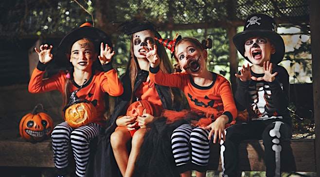 four kids outside in halloween costumes looking spooky