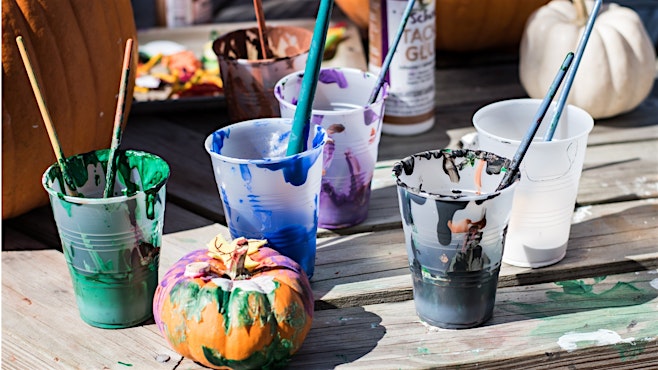 five paint cups outside with paintbrushes for halloween pumpkin activity