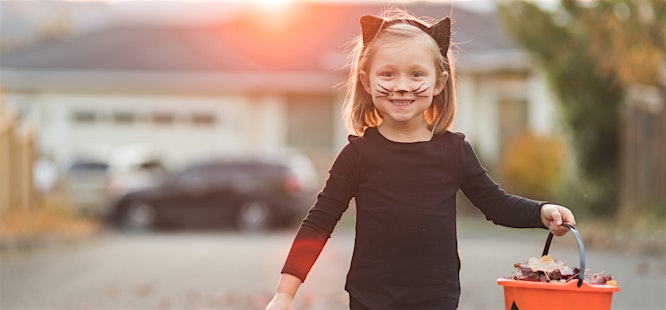 girl dressed as black cat for halloween with candy basket