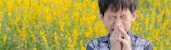 Boy with allergies in a field of flowers