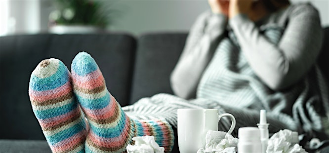 woman in comfy socks blowing her nose cold and flu