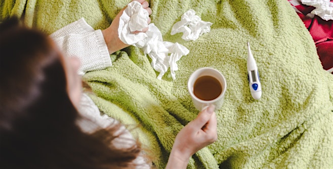 woman with respiratory illness in bed with tissues deciding to go to urgent care